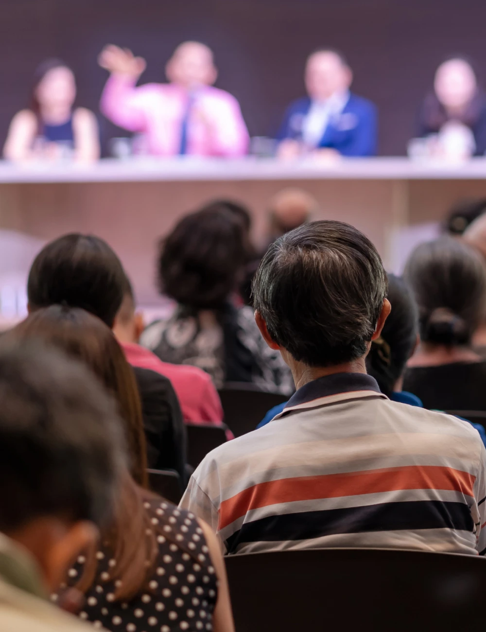 Audience seated facing a panel of four people speaking at a conference or seminar.